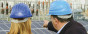 Two people point to solar panels in a construction site