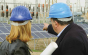 two people in hard hats on a building site pointing to solar panels